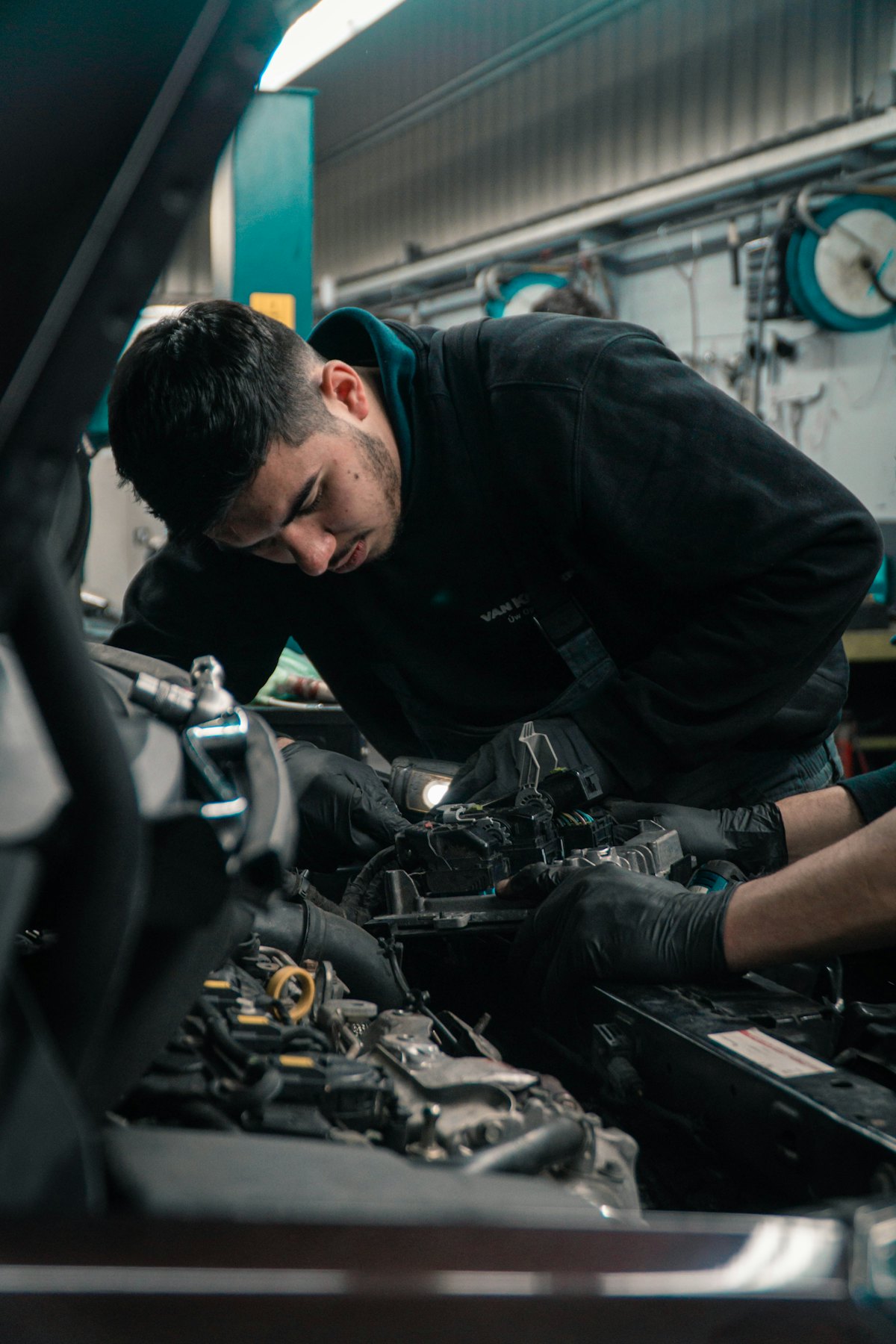 Mecânico instalando bateria no cofre do motor de um carro