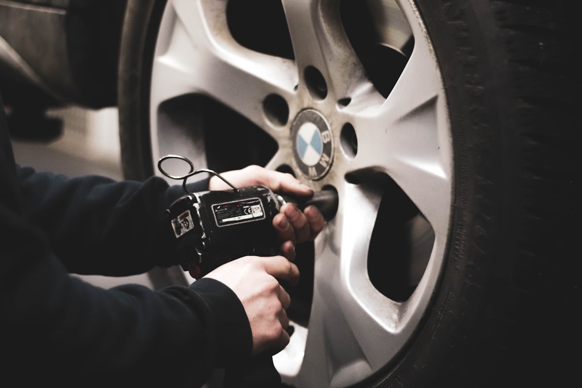 Profissional verificando a roda de um veículo com equipamento na mão
